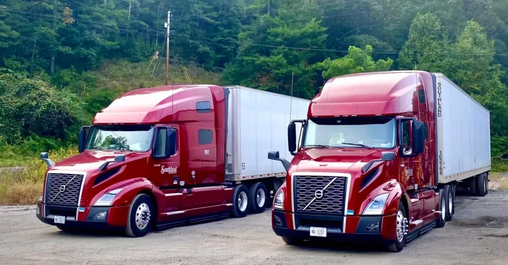 two Volvo trucks for OTR Company Drivers parked in scenic woods